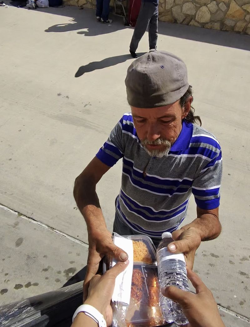 A man accepting a container of food and water from a volunteer