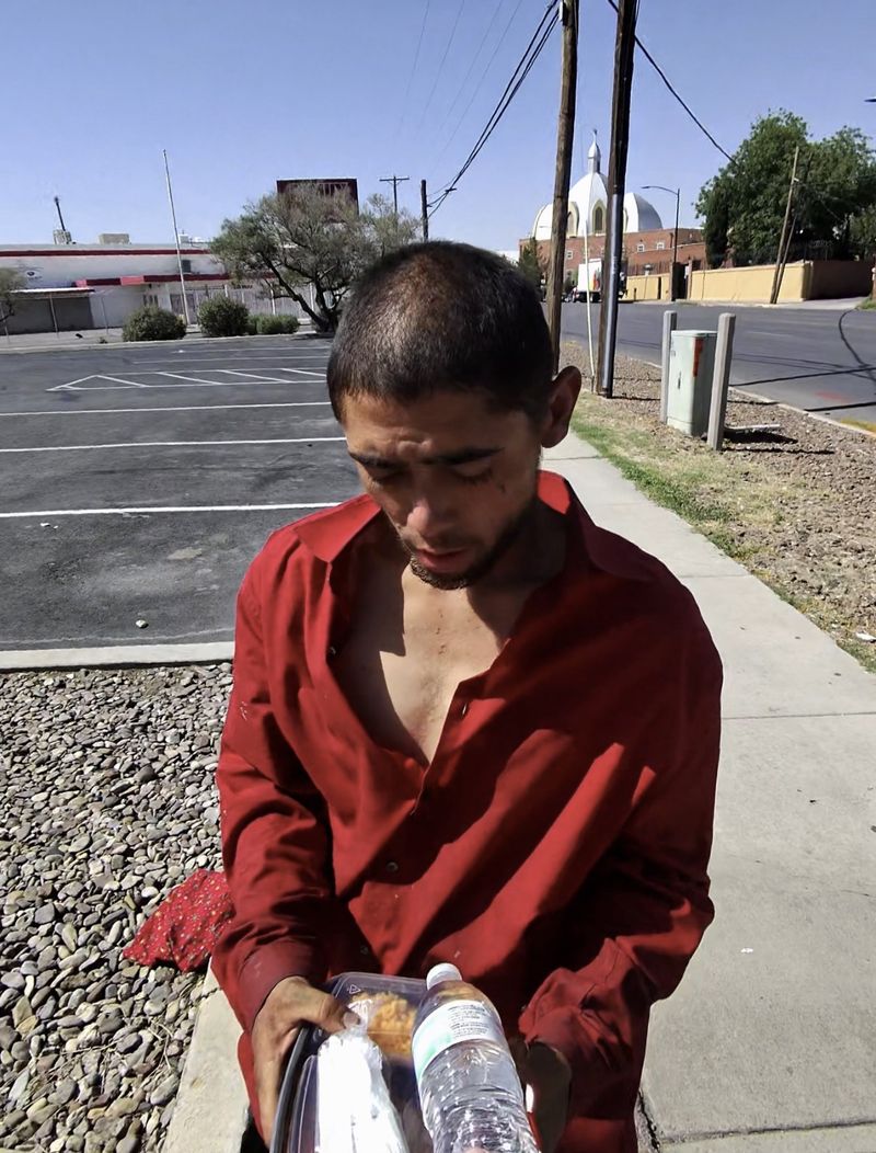 A man receiving food in a parking lot near a church